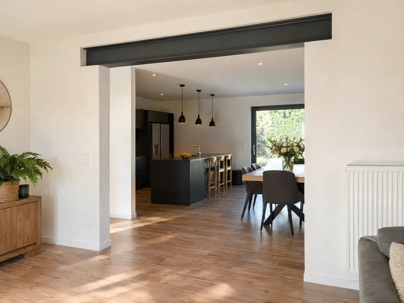 Rénovation d'appartement : salon-cuisine ouverts séparés par poutre noire, parquet bois